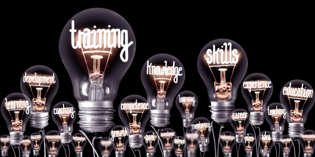 Light bulbs with shining fibres in a shape of TRAINING, SKILLS and KNOWLEDGE concept related words isolated on black background