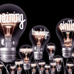 Light bulbs with shining fibres in a shape of TRAINING, SKILLS and KNOWLEDGE concept related words isolated on black background