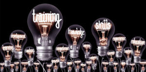Light bulbs with shining fibres in a shape of TRAINING, SKILLS and KNOWLEDGE concept related words isolated on black background
