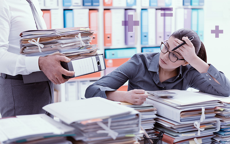 An accountant resting his head on his hand overwhelmed by paperwork due to their firm’s accounting staffing challenges