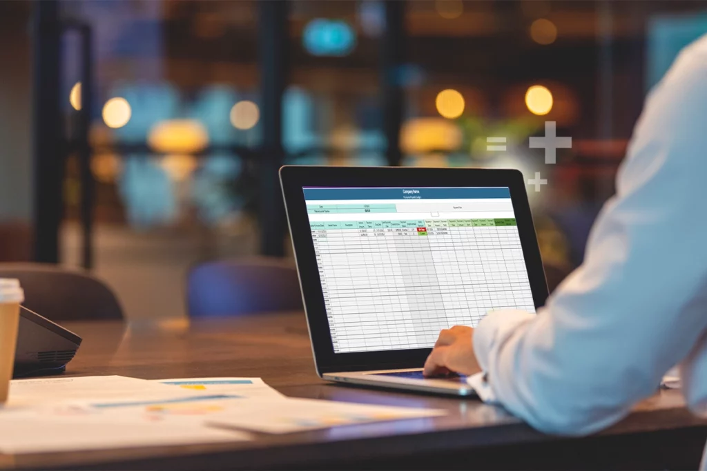 An accountant workspace with an accounts payable spreadsheet displayed on a laptop next to a calculator and invoices